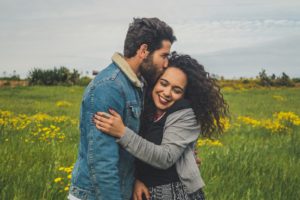 man kissing on woman's head on the green grassy field